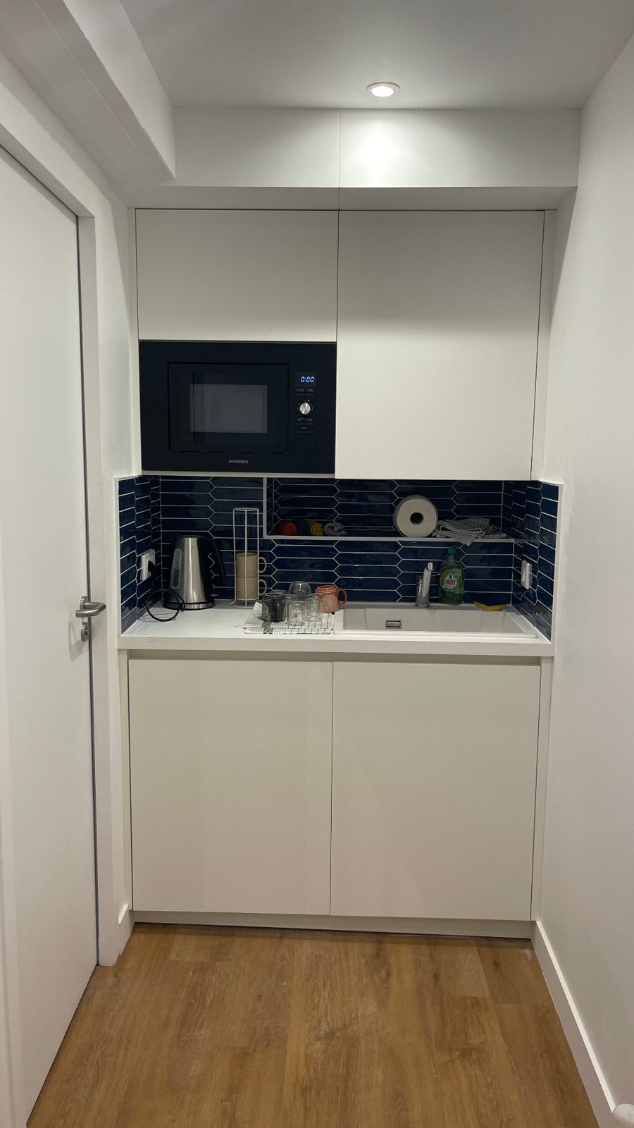 Kitchenette blanche, crédence bleue foncée