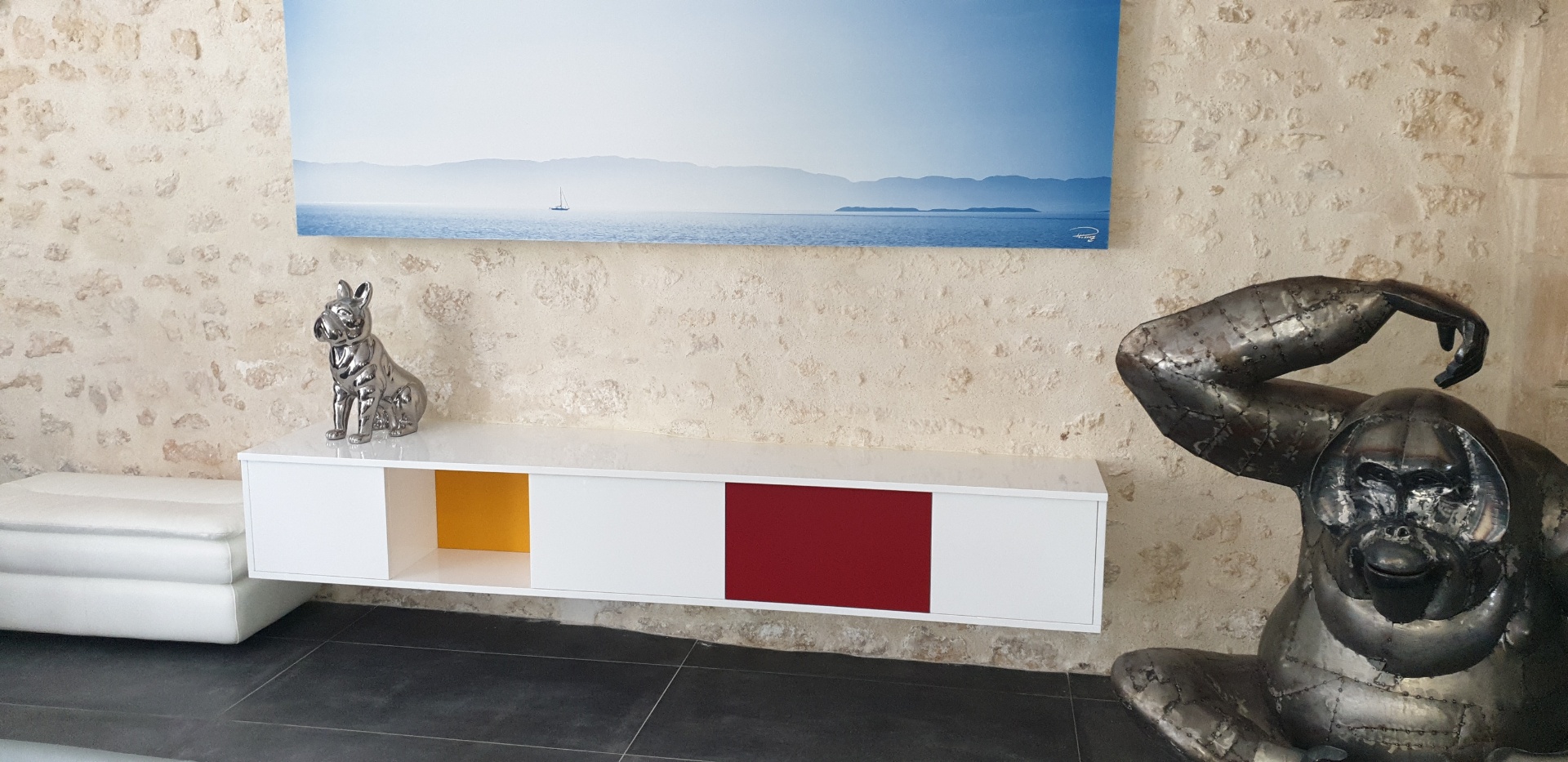 Buffet suspendu blanc à niches colorées, mur en pierre